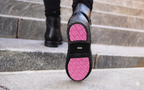 Xena Omega black work boots with pink-accent outsole, worn on steps